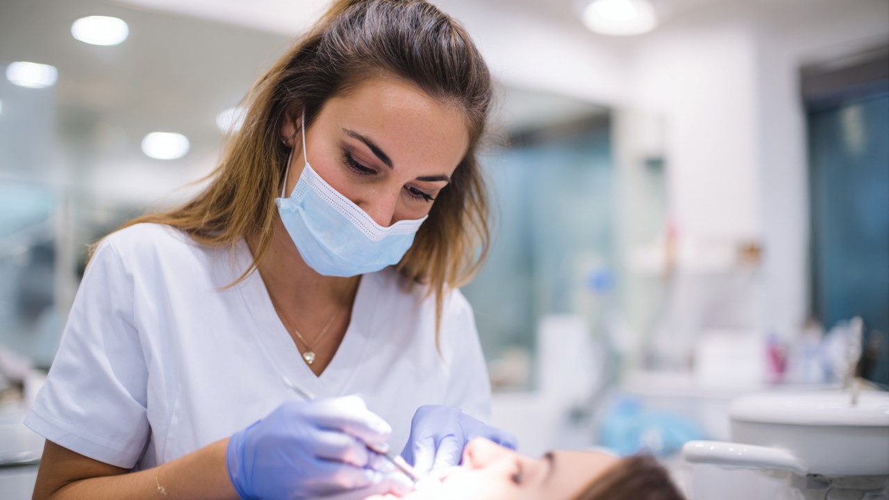 Close-up of a dental professional performing teeth cleaning with dental tools in a modern clinic, emphasizing oral hygiene and professional dental care.