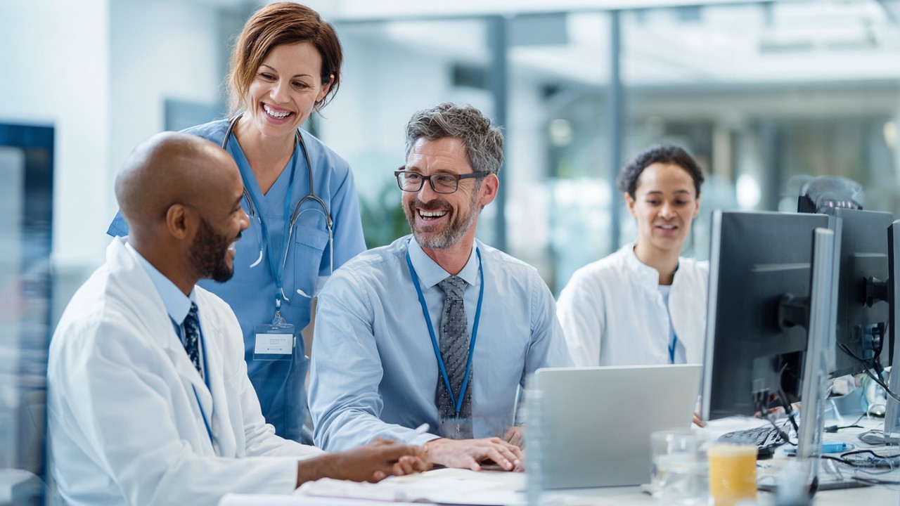 Modern healthcare clinic office with diverse medical professionals collaborating over digital devices in a bright, clean environment emphasizing trust and professionalism.