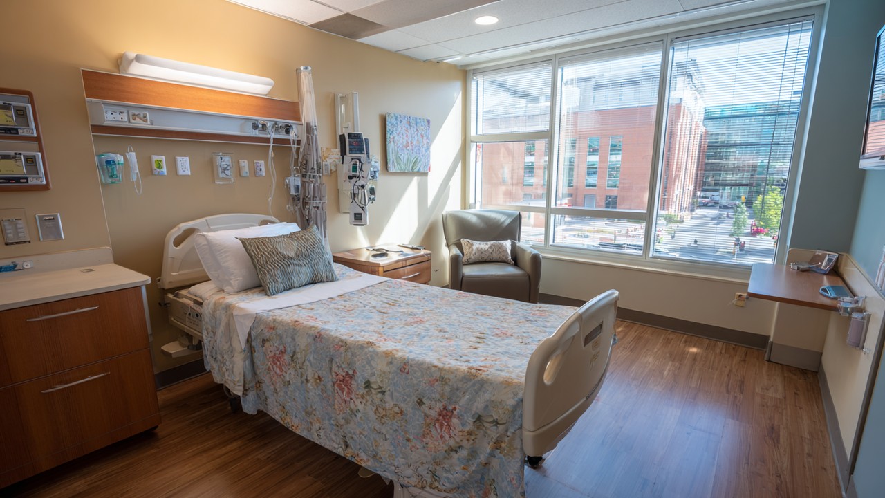 Helles, sauberes Krankenhauszimmer mit bequemem Bett, medizinischer Ausrüstung und großem Fenster, ideal für Gesundheitsreise-Patienten.