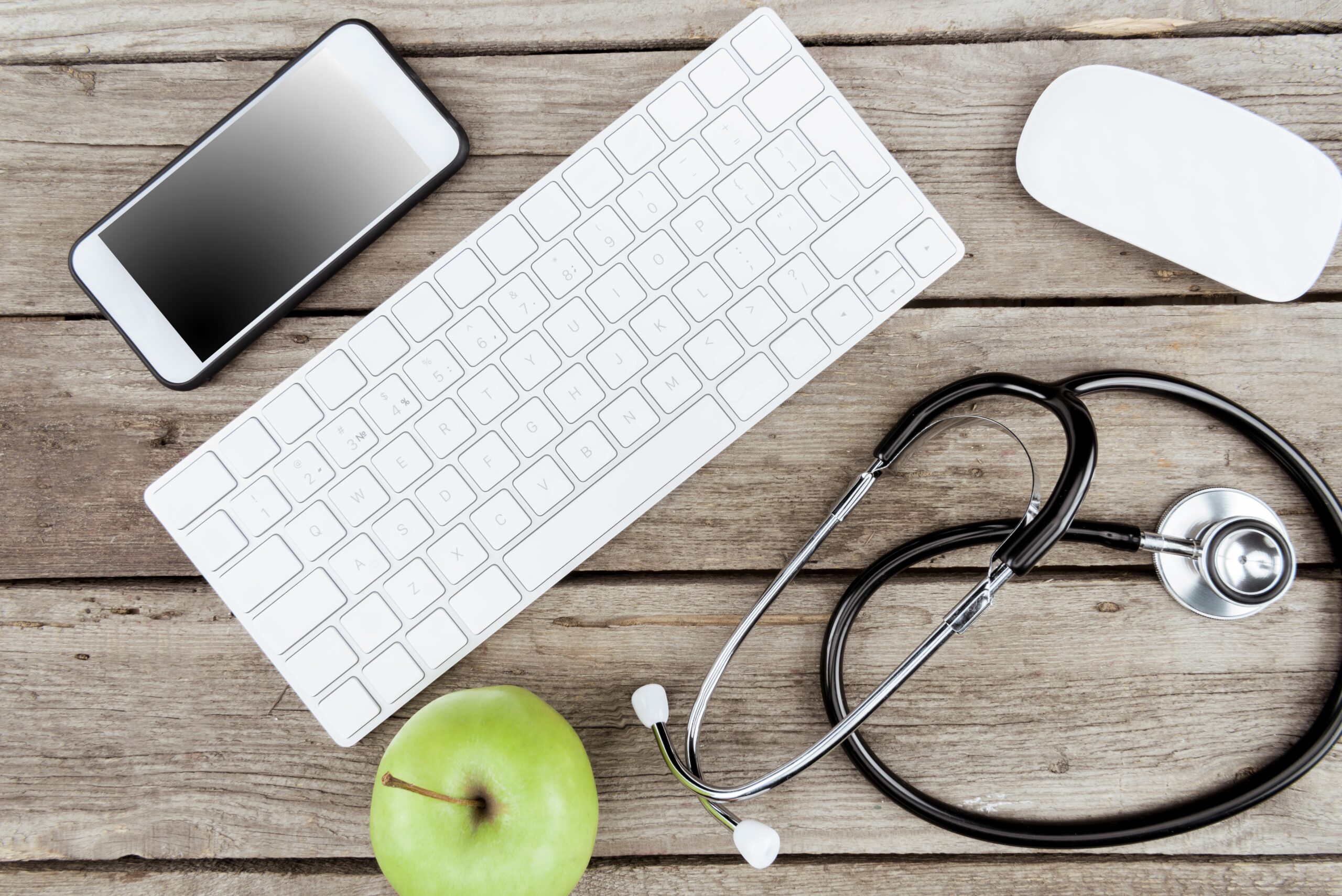 flat lay with digital devices, stethoscope and fresh apple on wooden table