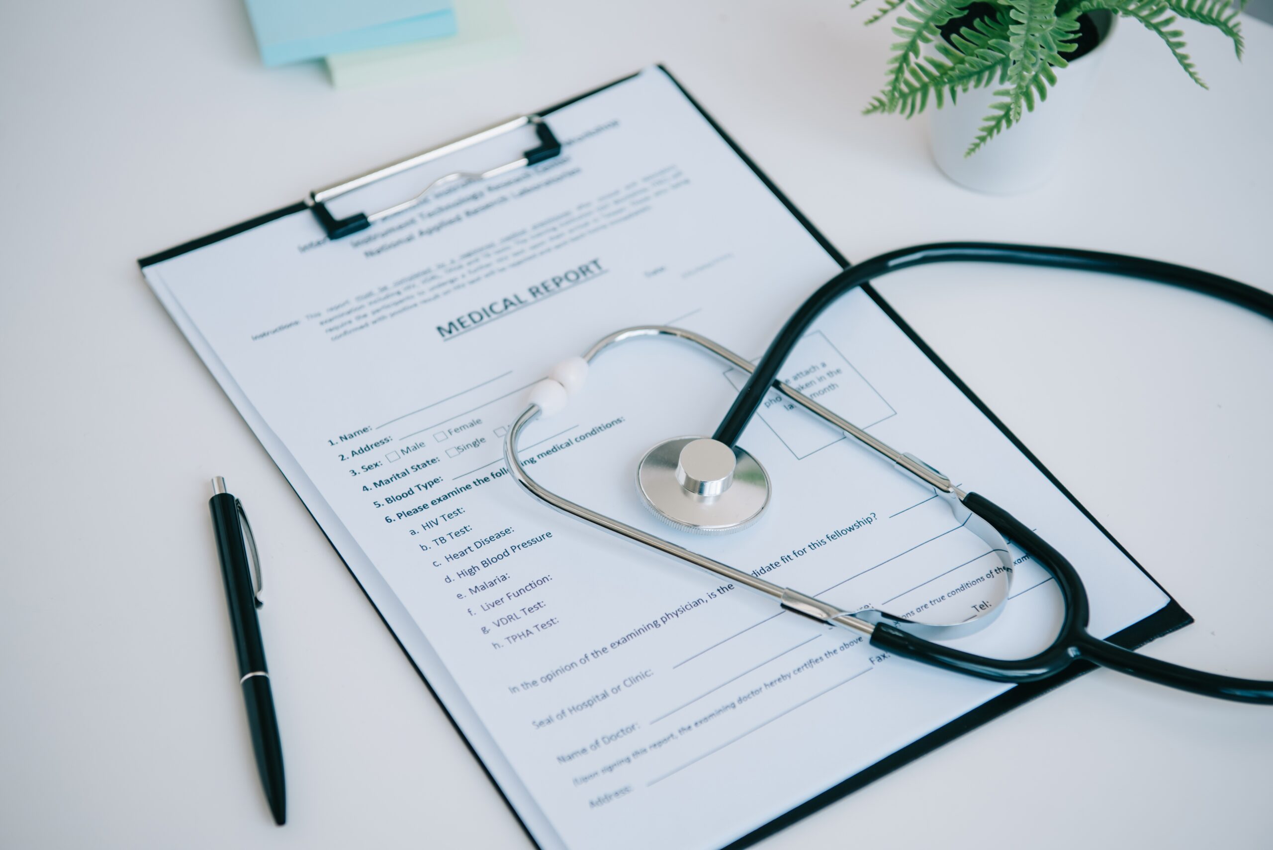 medical report, stethoscope and pen near flowerpot on white table