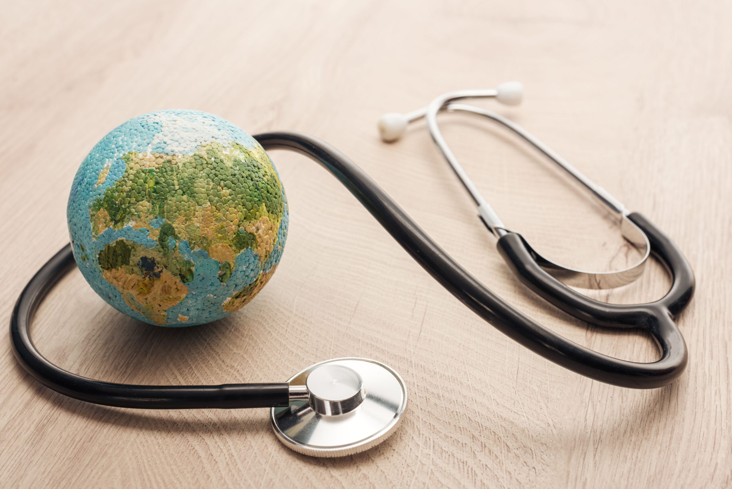 selective focus of stethoscope and toy earth on wooden and white table