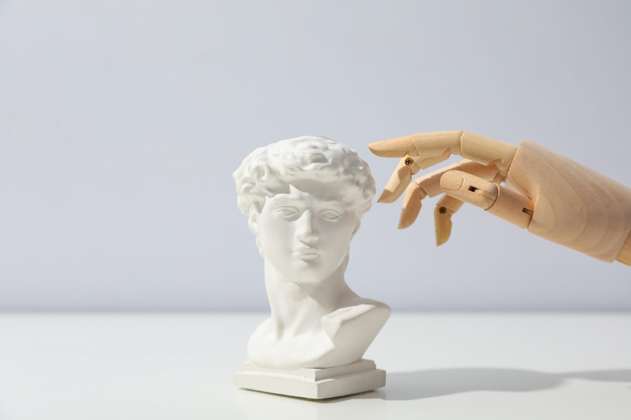 Wooden hand and ancient head on white table