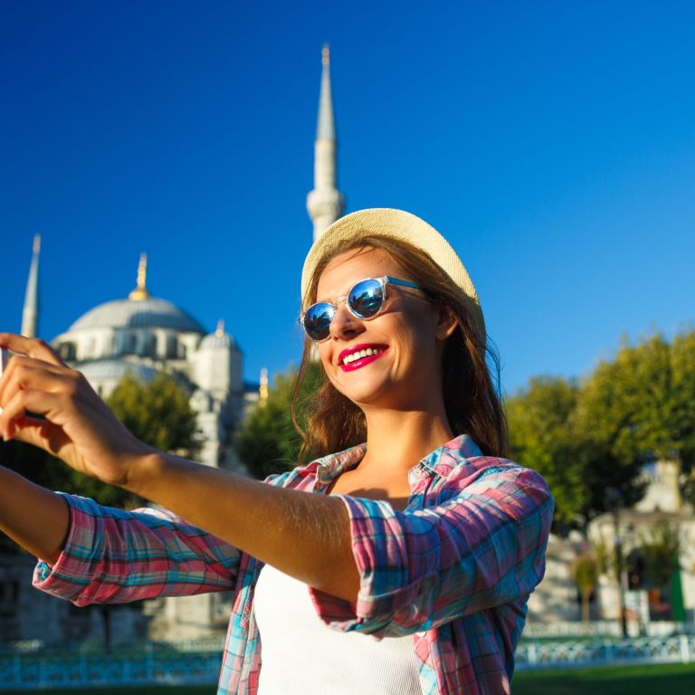 Girl in the hat making selfie by the smartphone on the backgroun
