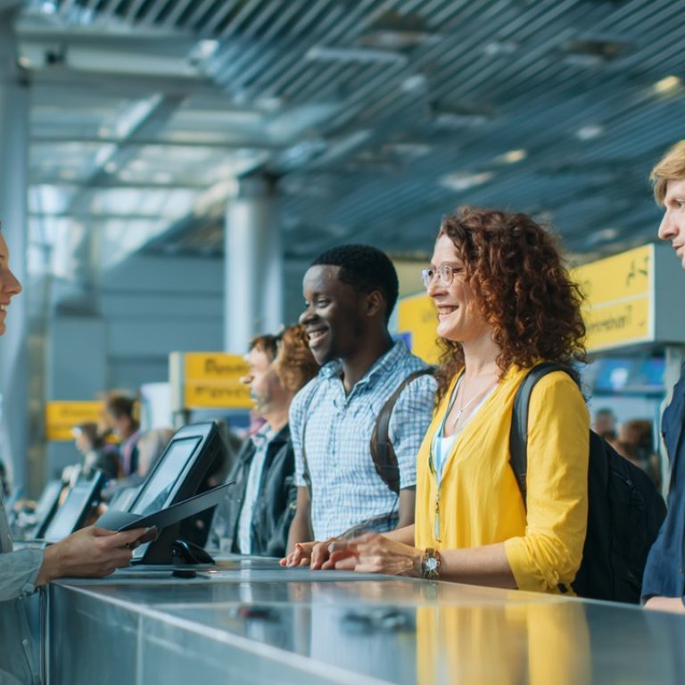 Uluslararası seyahat eden çeşitli kişiler, modern havaalanı vize ofisinde güler yüzlü memurla görüşerek sağlık seyahat hizmetleri alıyor.